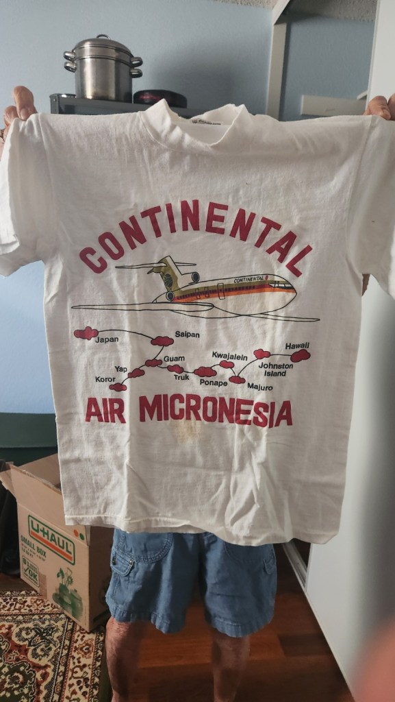 Original photo of my mom holding up my vintage Continental Air Micronesia T-shirt, with visible staining on the front.